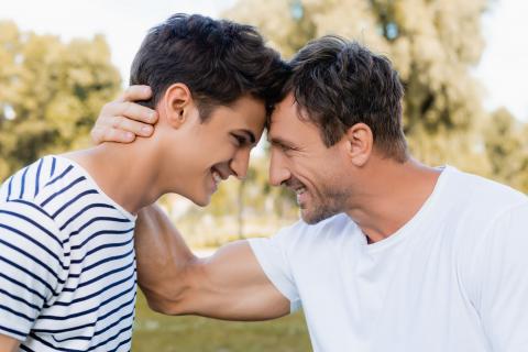 side view of joyful father and teenager son looking at each other