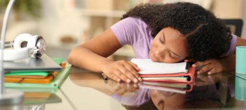Tired black student sleeping over notes at home