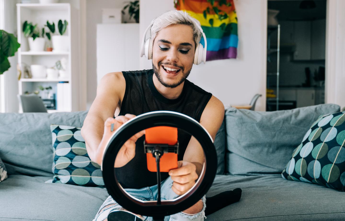 Influencer sitzt vor Handy mit Ringlicht und produziert Content.