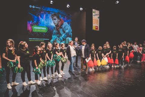 Moderator Siva und Teilnehmer des Trau-dich-Wettbewerbs auf der Bühne