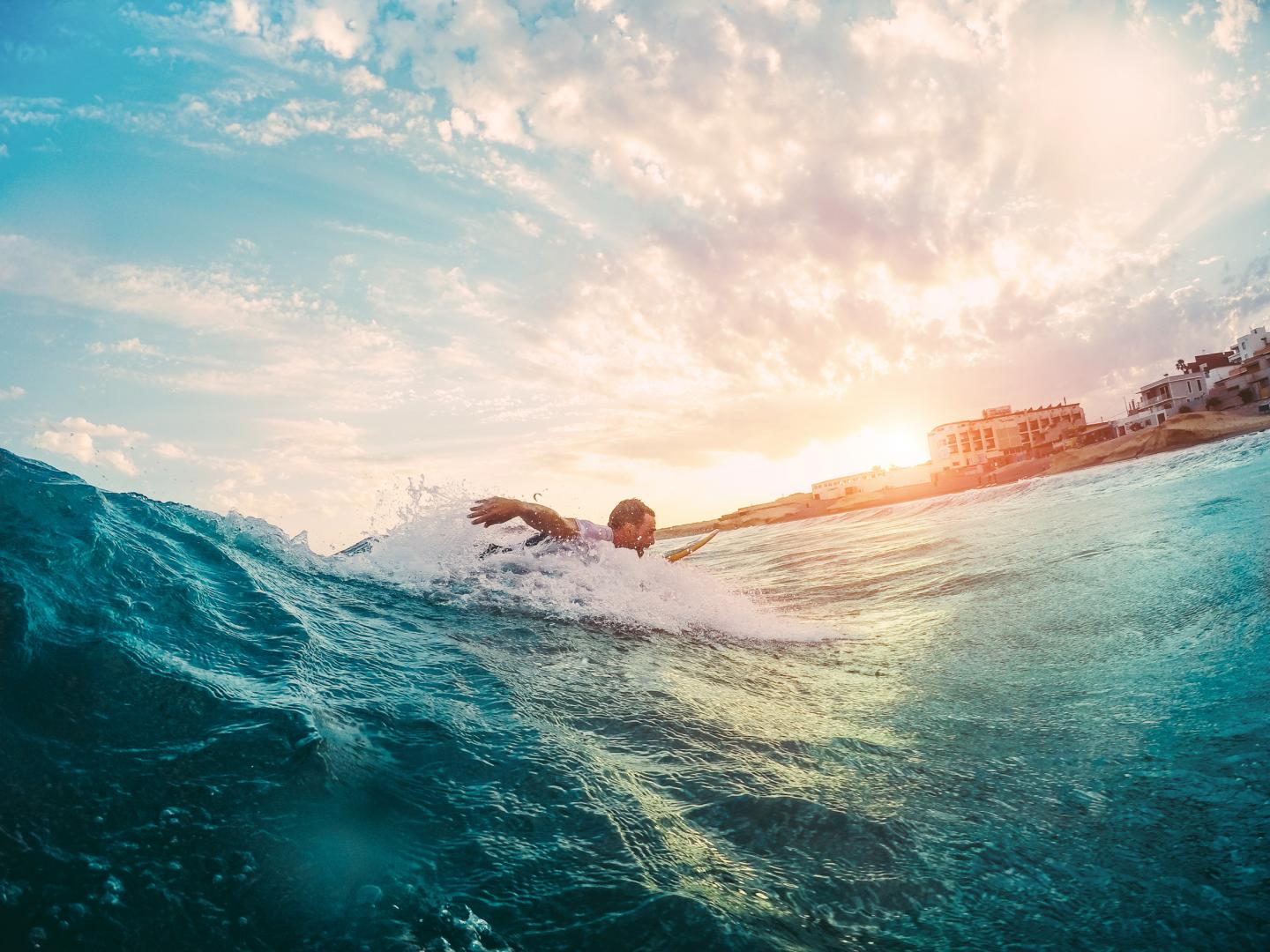 Ein Surfer reitet auf einer Welle bei Sonnenuntergang.