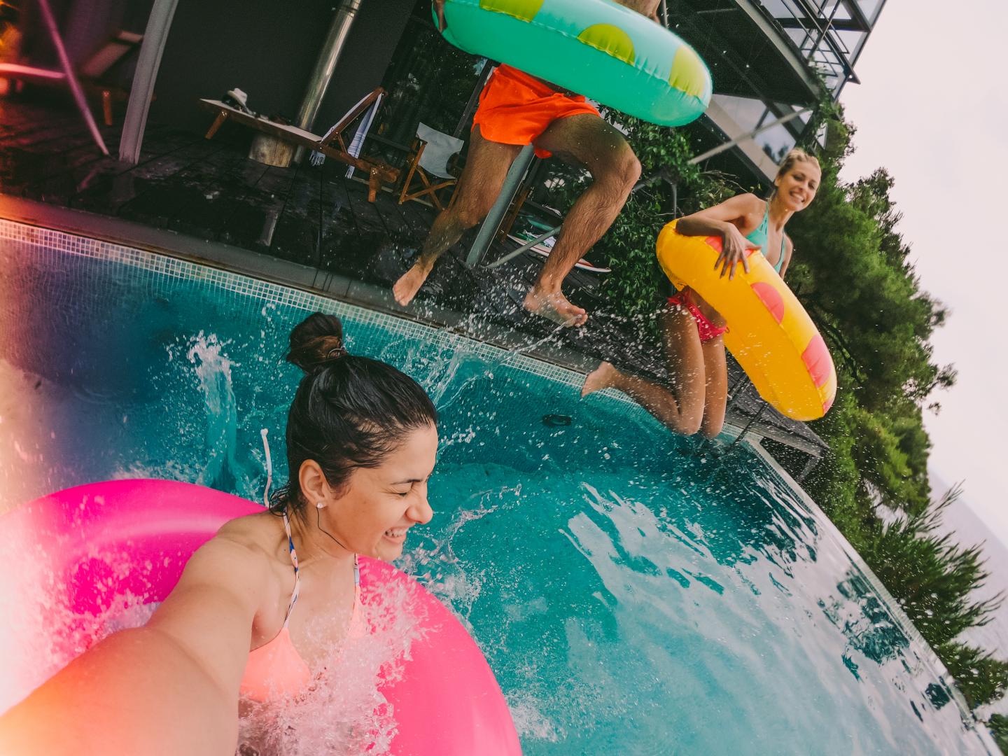 Eine Gruppe von Freunden springt in Schwimmringen in einem Pool.