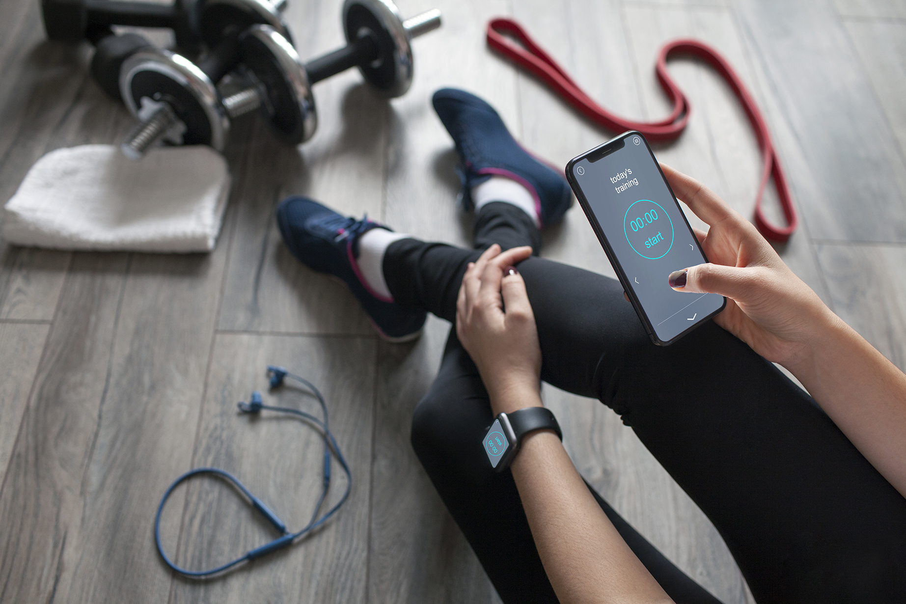 Eine Frau in Sportbekleidung hält ein Smartphone mit geöffneter Trainings-App