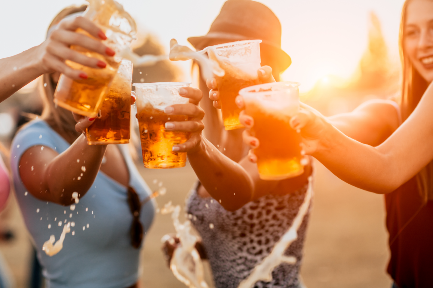 Eine Gruppe junger Frauen stößt auf einem Festival miteinander an.