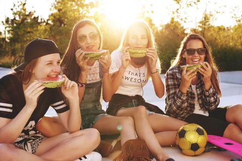 Vier Teenager-Mädchen teilen sich an einem sonnigen Sommerabend Wassermelone.