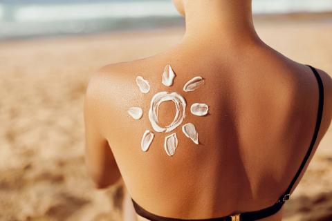 Aus Sonnencreme gemalte Sonne auf der Schulter einer jungen Frau.