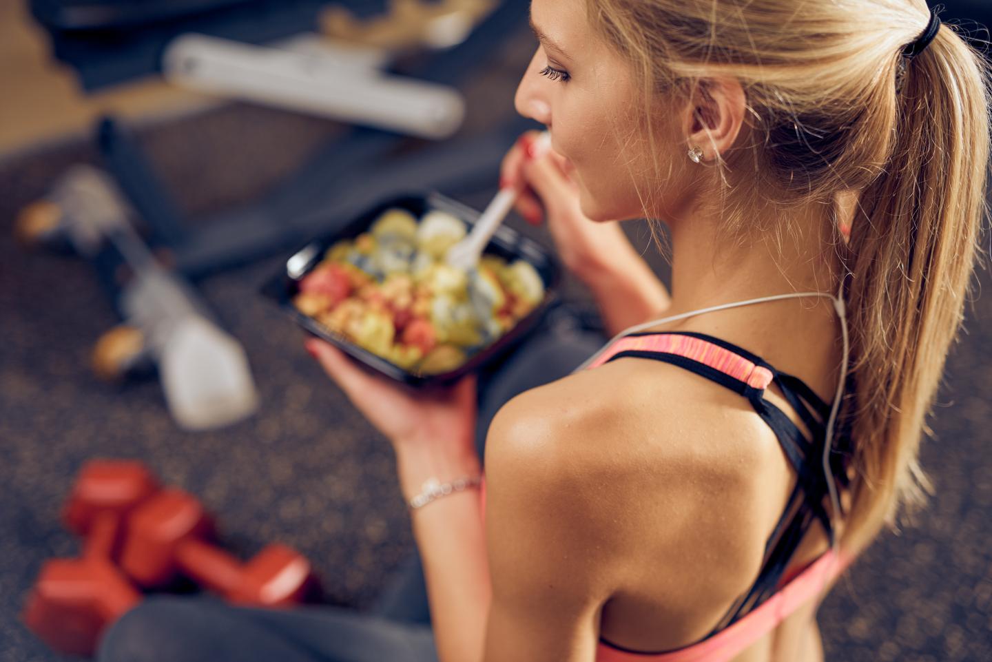 Junge Frau mit gesundem Snack im Fitnessstudio