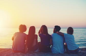 Freundesclique beim Sonnenuntergang am Meer