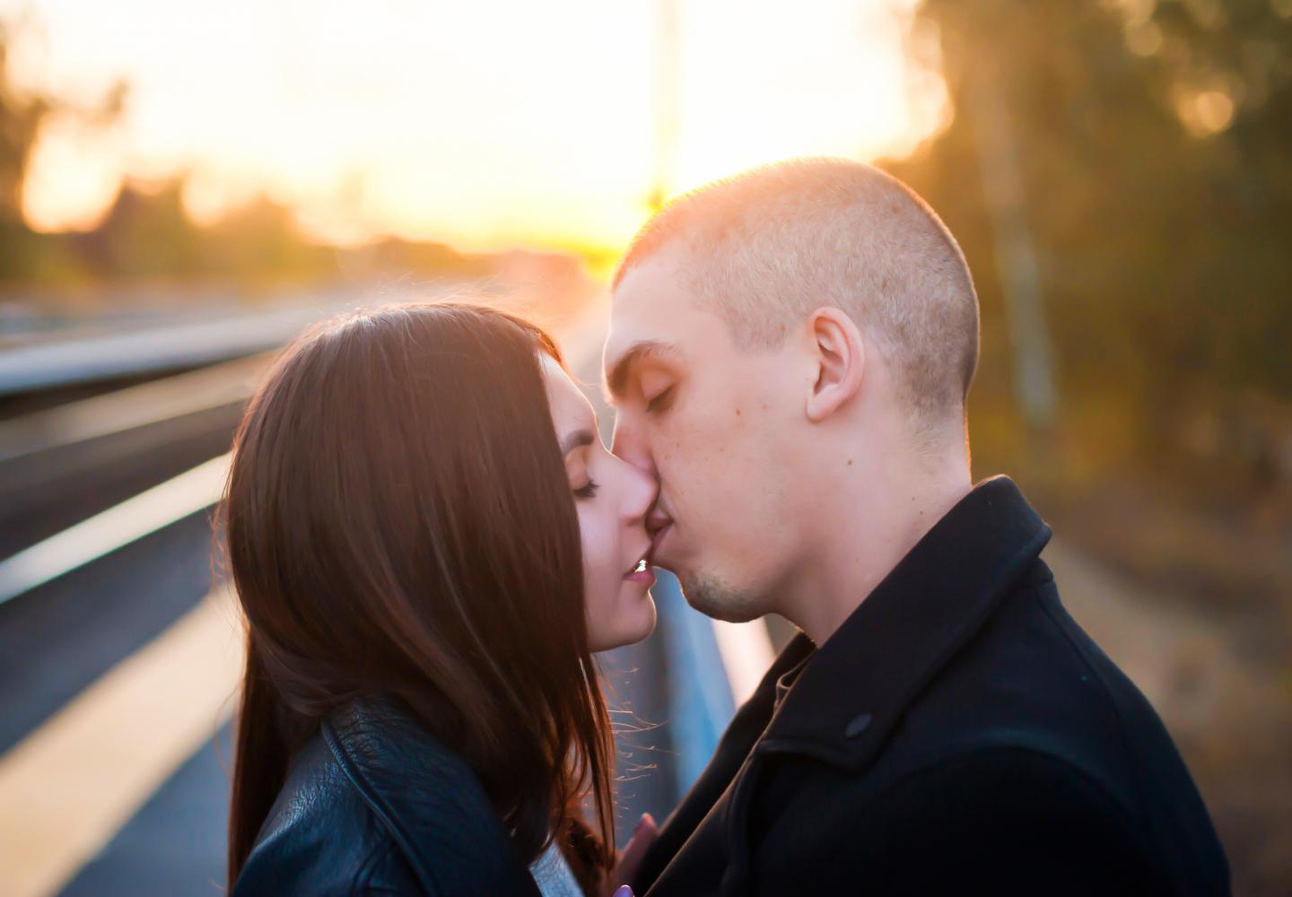 Junges Frau und junger Mann küssen sich vor dem Sonnenuntergang