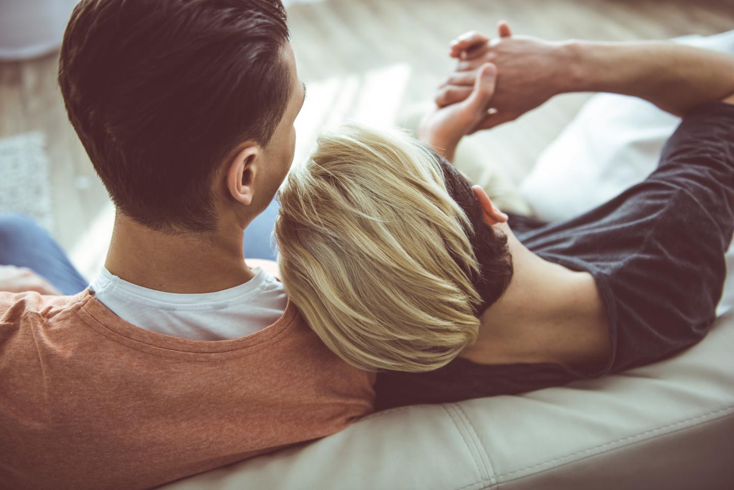 Zwei junge Männer kuscheln auf dem Sofa